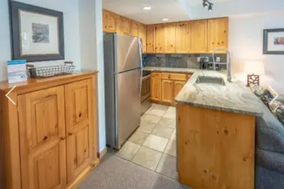 a kitchen with wooden cabinets and a stainless steel refrigerator at Whistler Steps to Village Sleeps 8 + Jacuz + Park in Whistler