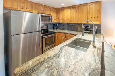 a kitchen with a stainless steel refrigerator and wooden cabinets at Whistler Steps to Village Sleeps 8 + Jacuz + Park in Whistler