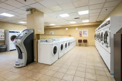 a laundry room with a row of washers and dryers at Prime Hotel in Fort McMurray
