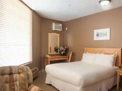a bedroom with a large white bed and a chair at Prime Hotel in Fort McMurray