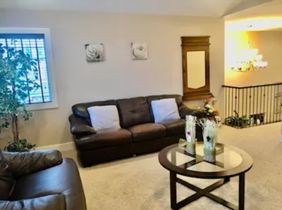a living room with a leather couch and a table at Luxury 3700 sq/ 5 bedroom/ jettedtub/ 4 fireplaces in Edmonton