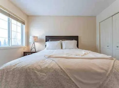a large bed in a white bedroom with a window at 2500 sq house in Springbank Hill BL 261818 in Calgary