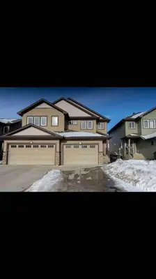 a large house with two garage doors in the snow at Cheerful and beautiful 3 bedroom home close lake in Edmonton
