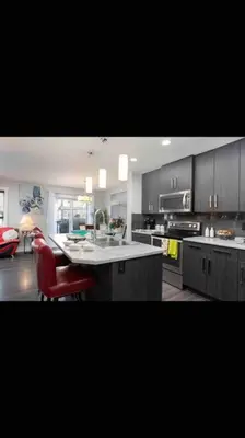 a kitchen with a counter and a red chair in it at Cheerful and beautiful 3 bedroom home close lake in Edmonton