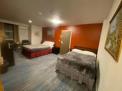 a hotel room with two beds and orange walls at Coldwater Hotel in Merritt