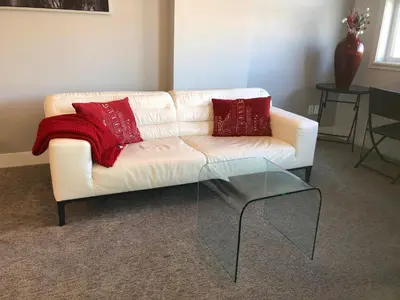 a white couch with two red pillows and a glass table at Amicable, Cozy, High Speed Internet, Sleeps 2 Riverview Downtown Apartment in Calgary