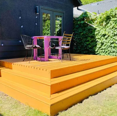 a deck with two chairs and a table on it at Trendy Kensington 3 min Walk Backyard AC Garage in Calgary