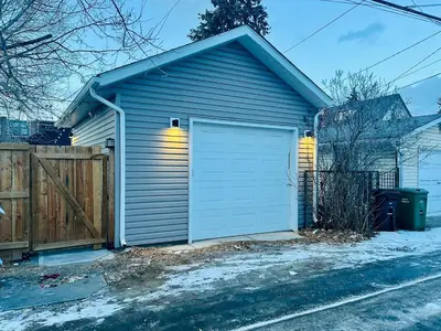 a garage with a white door on the side of a house at Trendy Kensington 3 min Walk Backyard AC Garage in Calgary