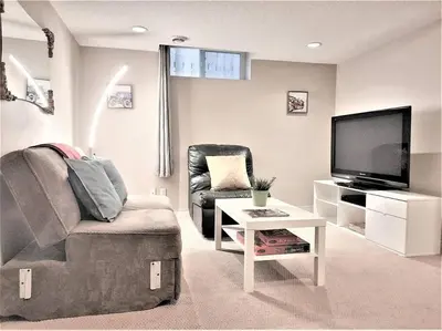 a living room with a couch and a tv and a chair at Stylish Getaway by Spruce Meadows in Calgary