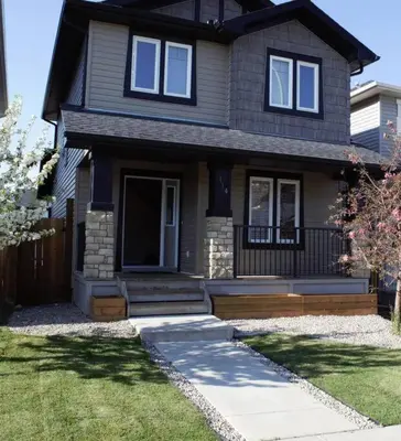 a black house with a front porch and a lawn at Stylish Getaway by Spruce Meadows in Calgary