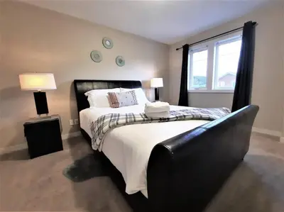 a bedroom with a large bed and a window at Stylish Getaway by Spruce Meadows in Calgary