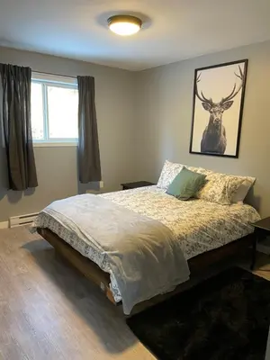 a bedroom with a bed with a deer picture on the wall at Sunrise Mountain view Skidegate House in Skidegate