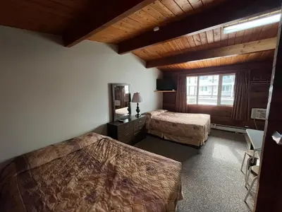 a hotel room with two beds and a window at Raccoon Lodge Motel in Sylvan Lake