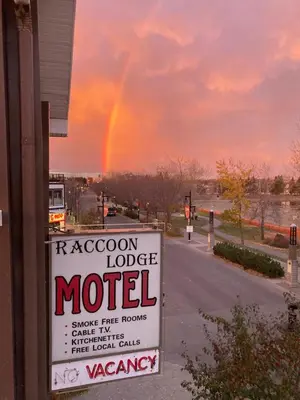 a rainbow in the sky behind a motel sign at Raccoon Lodge Motel in Sylvan Lake