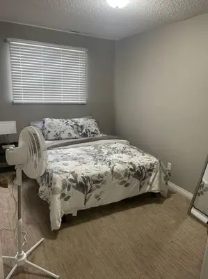 a bedroom with a bed with a fan and a window at Wonderful 2-bedroom apartment in Camrose