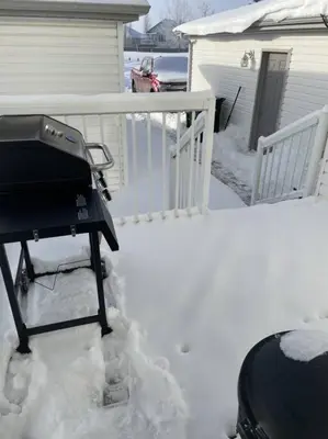 a grill sitting on a porch in the snow at Cozy Home in Camrose