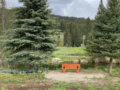 a wooden bench in a field next to a lake at Witt's End Ranch Private Get Away in Princeton