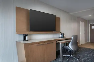 a room with a desk with a television on a wall at Courtyard by Marriott Nanaimo in Nanaimo
