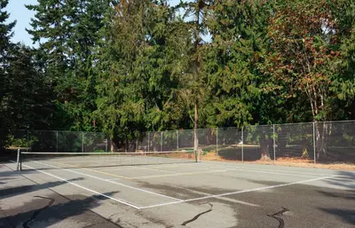 a tennis court with trees in the background at Sunrise Cove Apt at Inn of The Sea in Ladysmith