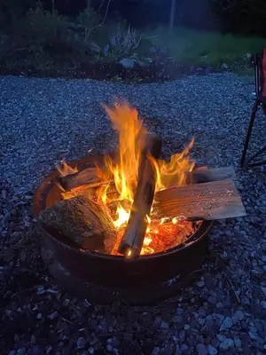 a fire in a pot with a wooden spatula at Beaver Lake Resort Site #36 in Lake Cowichan