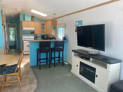 a living room with a flat screen tv and a kitchen at Beaver Lake Resort Site #36 in Lake Cowichan