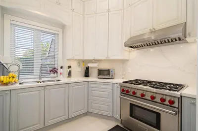 a kitchen with white cabinets and a stove top oven at Vancouver Shangrila House in Richmond