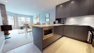 a kitchen with brown cabinets and a living room at 260 The Aspens - Ski In Ski Out in Whistler