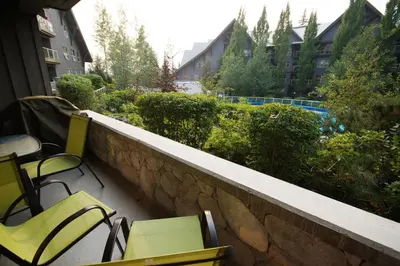 a balcony with chairs and a stone wall at 260 The Aspens - Ski In Ski Out in Whistler