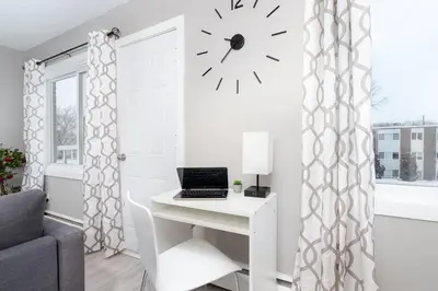 a room with a desk with a clock on the wall at Modern & Stylish 1-Bedroom Unit in Edmonton
