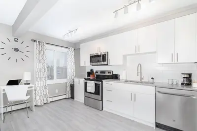 a kitchen with white cabinets and a table and a clock at Modern & Stylish 1-Bedroom Unit in Edmonton