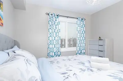 a bedroom with a bed with blue curtains and a window at Modern & Stylish 1-Bedroom Unit in Edmonton