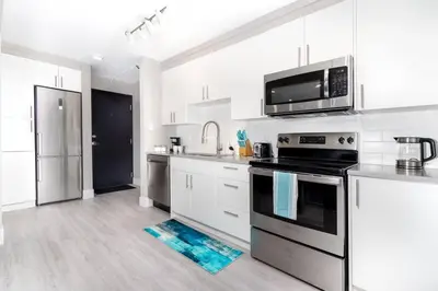 a kitchen with stainless steel appliances and white cabinets at Modern & Stylish 2-Bedroom Unit in Edmonton