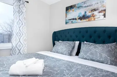 a bedroom with a bed with a blue headboard and pillows at Modern & Stylish 2-Bedroom Unit in Edmonton