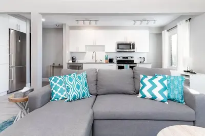 a living room with a gray couch with blue and white pillows at Modern & Stylish 2-Bedroom Unit in Edmonton