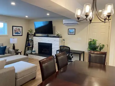 a living room with a table and a fireplace at Bright poolside walkout two bedroom basement suite in the Okanagan in Penticton