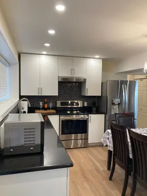 a kitchen with white cabinets and stainless steel appliances at Bright poolside walkout two bedroom basement suite in the Okanagan in Penticton
