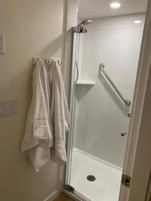a bathroom with a shower with white towels at Bright poolside walkout two bedroom basement suite in the Okanagan in Penticton