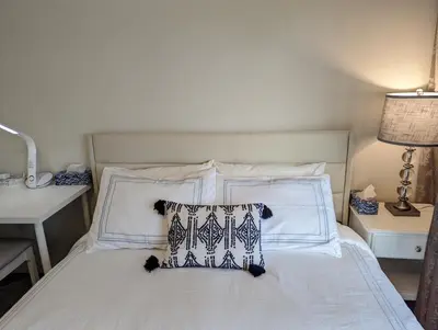 a bed with white sheets and pillows on it at Nice home away at Vancouver near YVR in Vancouver