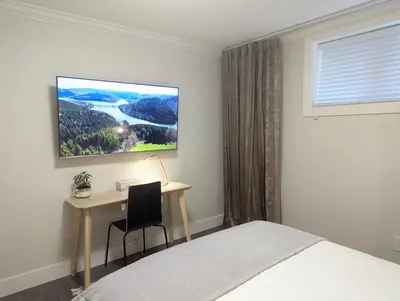 a bedroom with a bed and a desk with a monitor at Nice home away at Vancouver near YVR in Vancouver