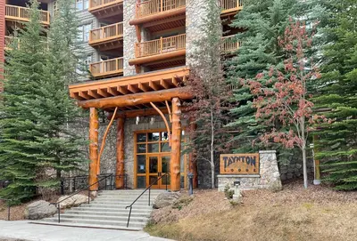 a resort building with a wooden entrance and stairs at Perfect Ski or Bike in-out Hot Tub Pool in Panorama