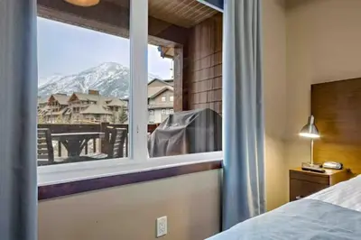 a bedroom with a window with a view of a mountain at Falcon Crest Lodge 1 BR Condo With Gym & Hot-Tubs & Mountain View in Canmore