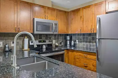 a kitchen with wooden cabinets and a stainless steel refrigerator at Falcon Crest Lodge 1 BR Condo With Gym & Hot-Tubs & Mountain View in Canmore