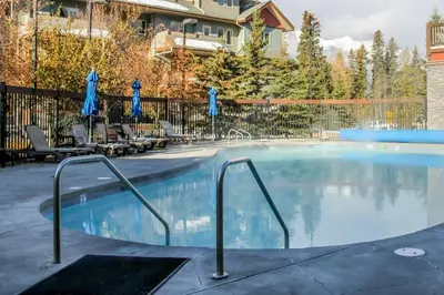 a large swimming pool with chairs and umbrellas at Mountain Retreat - Modern and Bright with Panorama Views 2 bedrooms, 4 beds, heated all-year outdoor pool, hottub, balcony, Banff Park Pass in Canmore