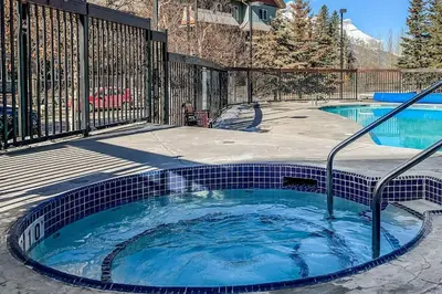 a hot tub in a backyard with a fence at Mountain Retreat - Modern and Bright with Panorama Views 2 bedrooms, 4 beds, heated all-year outdoor pool, hottub, balcony, Banff Park Pass in Canmore