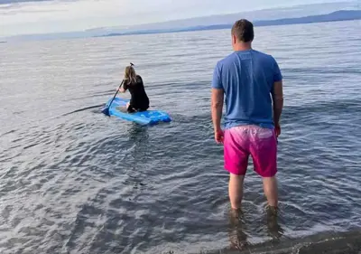 a man and a dog on a paddle board in the water at Oceanside Manor - Golf Course View in Qualicum Beach