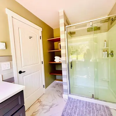 a shower with a glass door in a bathroom at Oceanside Manor - Golf Course View in Qualicum Beach