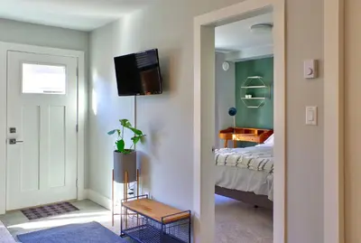 a bedroom with a bed and a television on a wall at Zen Retreat Langford in Victoria