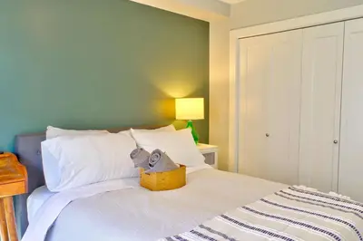 a bed with a basket with a stuffed animal on it at Zen Retreat Langford in Victoria