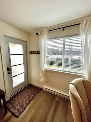 a living room with a large window and a chair at Cozy Lakeview Suite in Victoria
