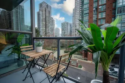 a balcony with a table and chairs and a view of a city at Heart of Downtown King Suite/Parkng/Pool/Gym/Sauna in Vancouver